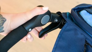 Releasing the stroller frame for folding requires squeezing both...