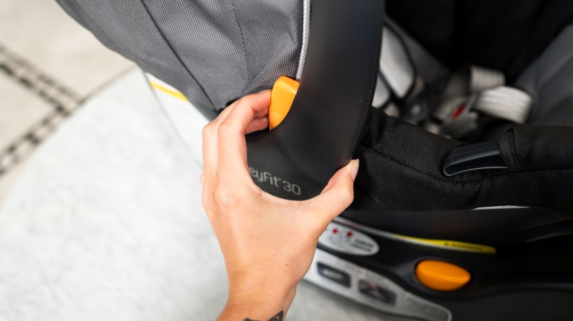 chicco keyfit 30 - adjusting the handle on the keyfit 30 is a two-hand operation by...
